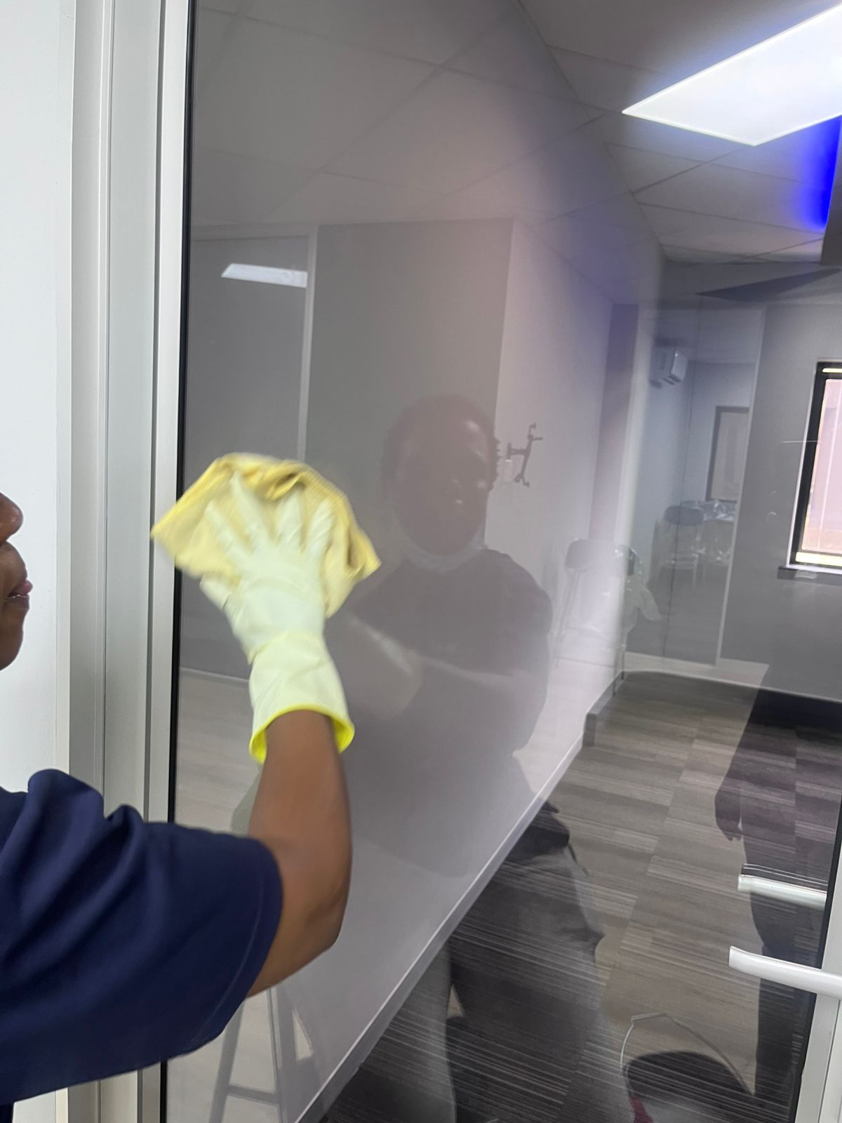 Close-up of gloved hand wiping down frosted glass